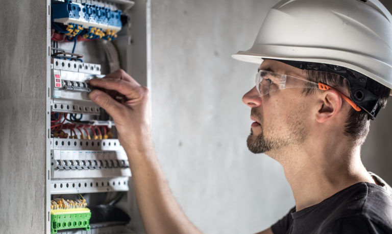 man-electrical-technician-working-switchboard-with-fuses-installation-connection-electrical-equipment